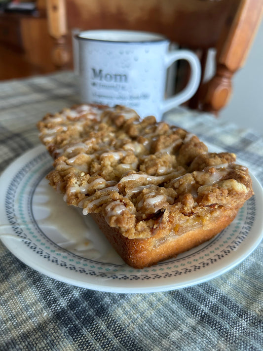 Mini Apple Coffee Cake loaf on a white plate with a white mug of coffee in the background 