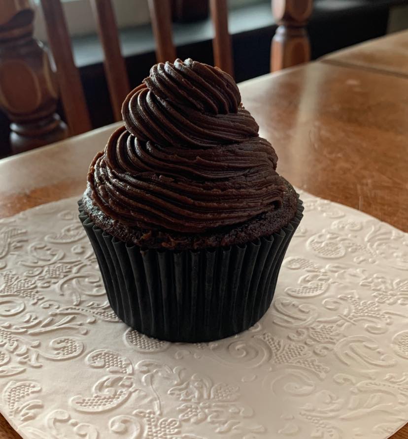 Single Chocolate cupcake with chocolate buttercream swirl on a pink napkin