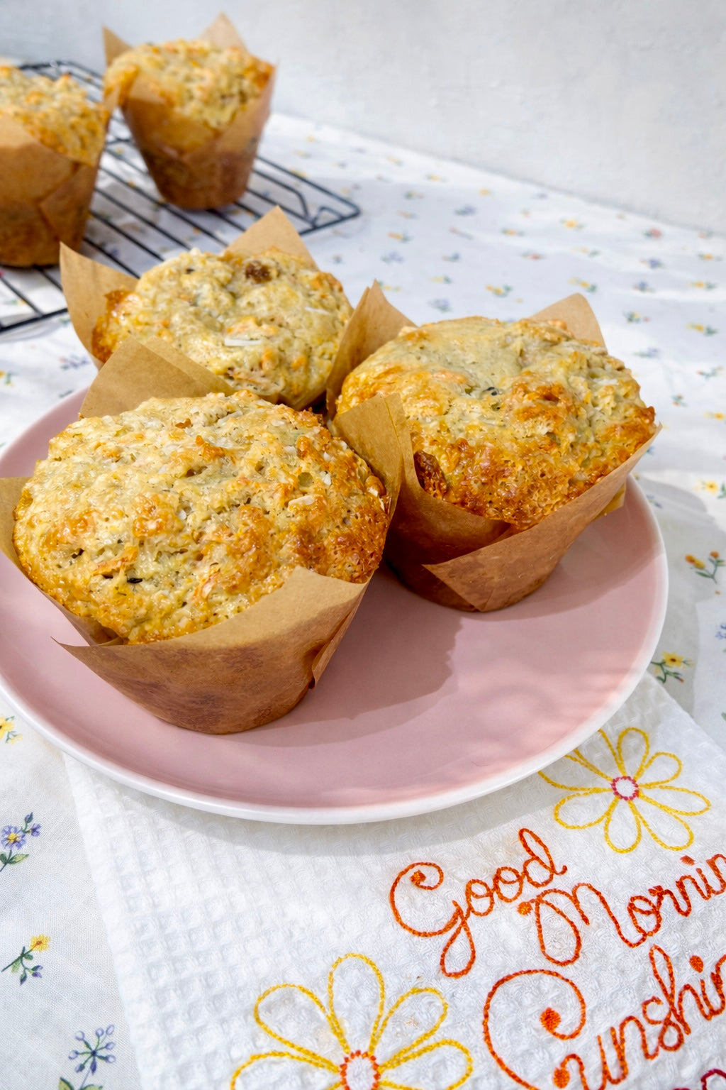 Muffins on a pink plate with a floral towel underneath