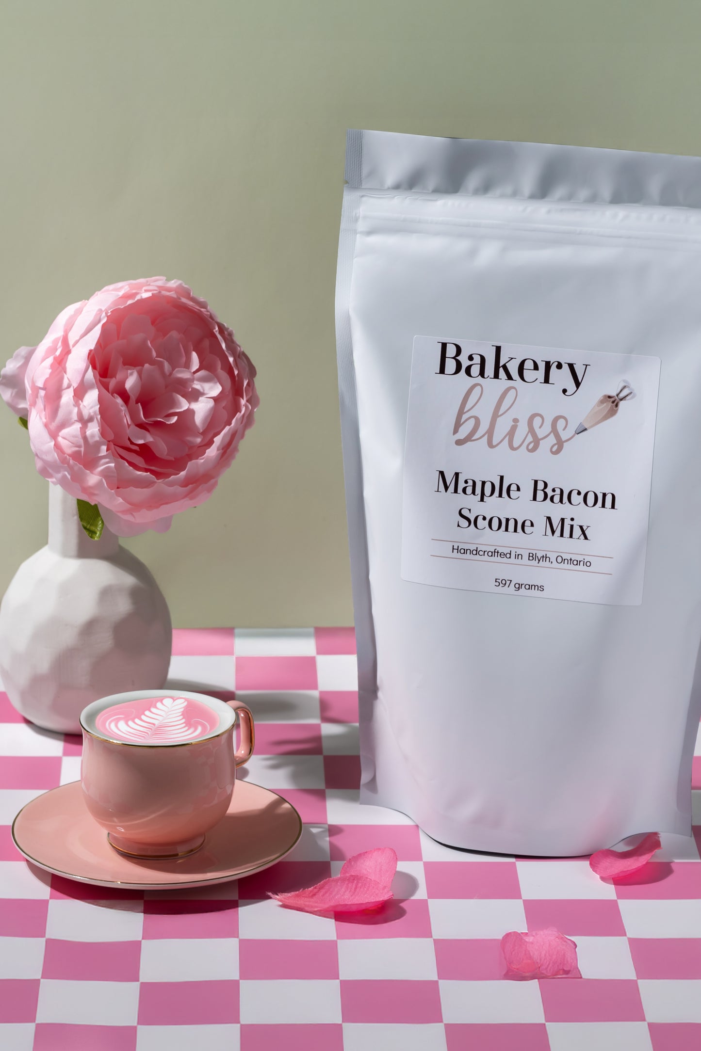 Bakery bliss Maple Bacon Scone Mix package on a checkered tablecloth with a pink cup and flower.