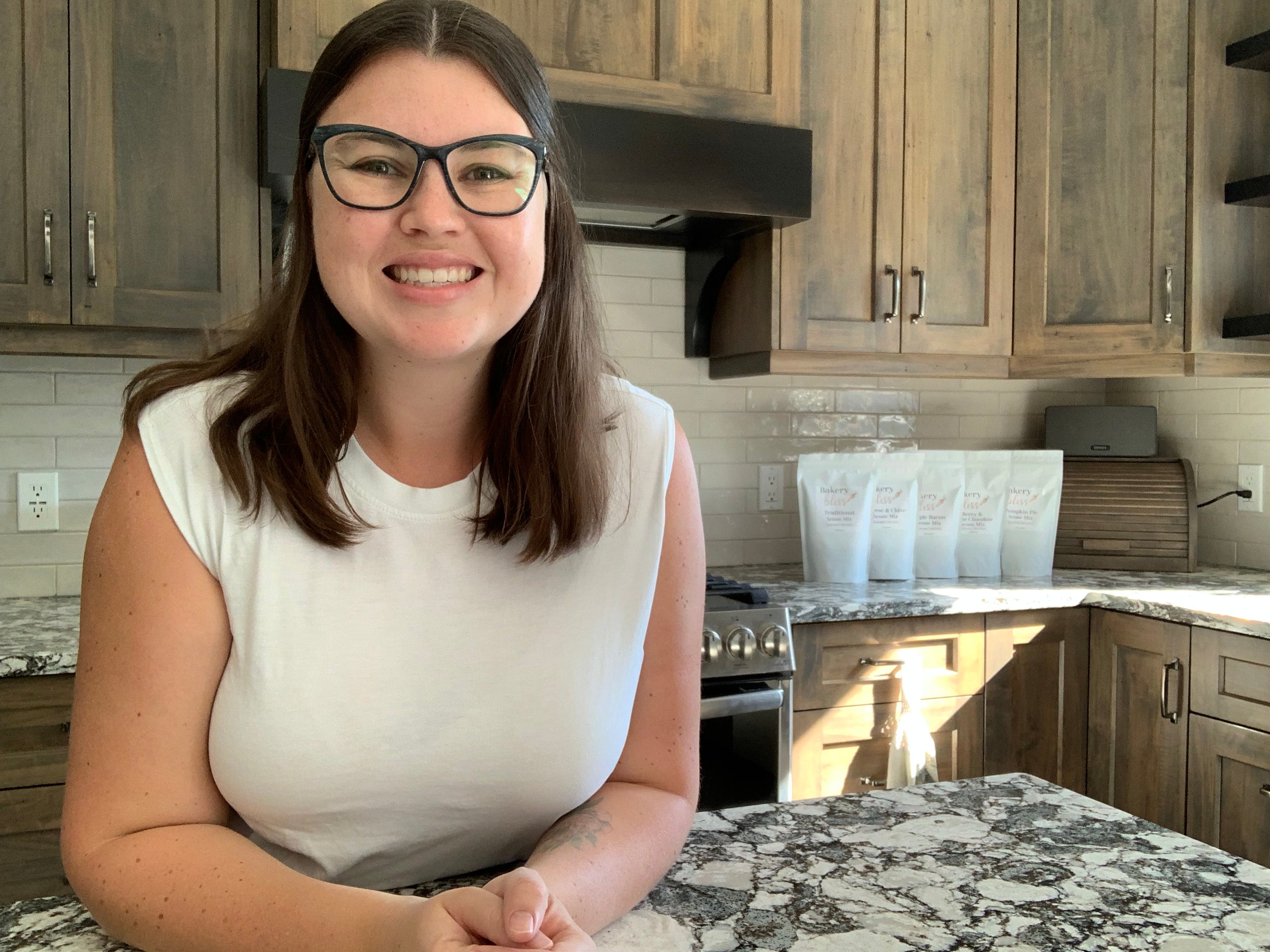 Jessica in a kitchen with wooden cabinets and a marble countertop.