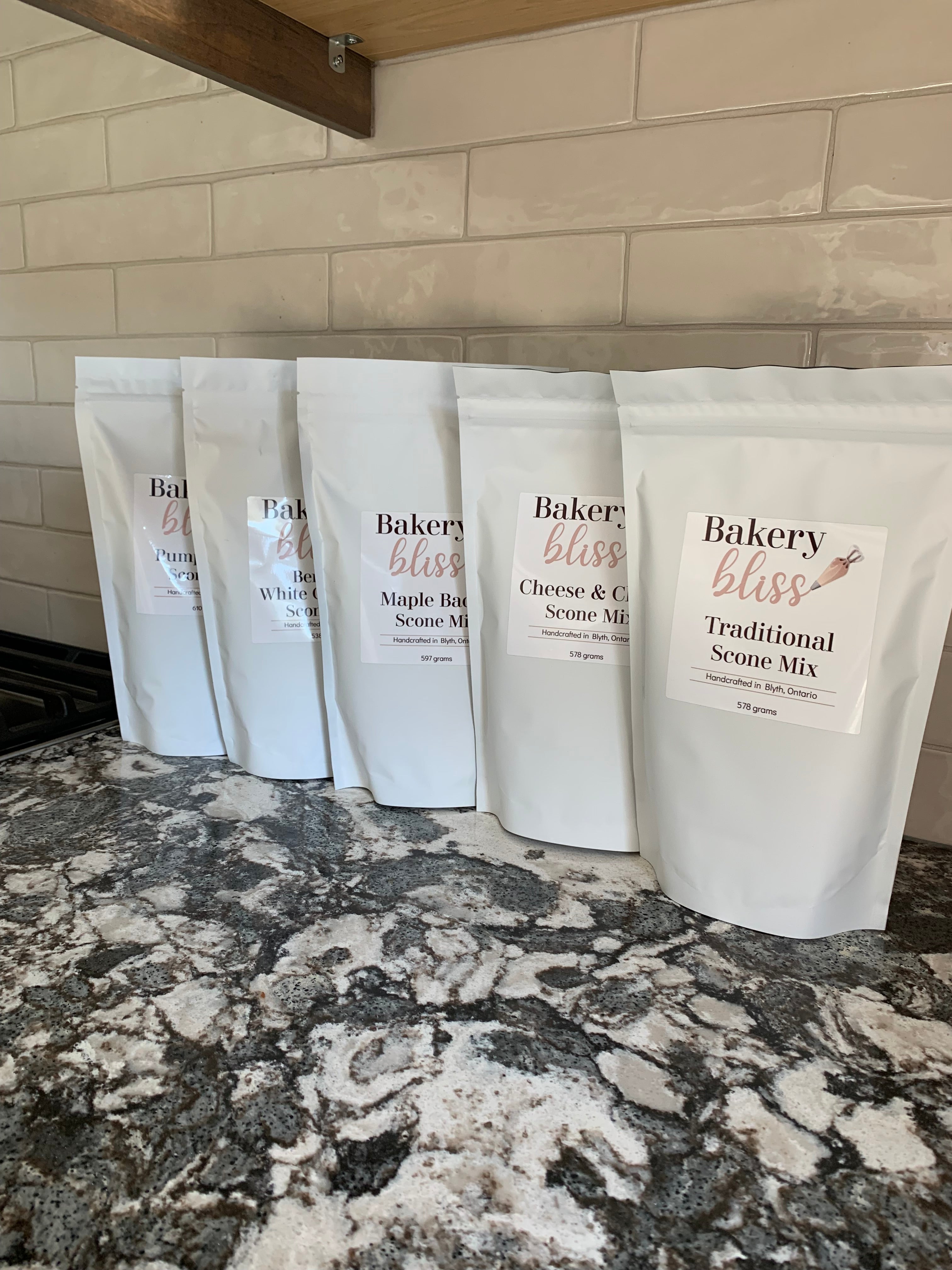 Multiple bags of 'Bakery Bliss' mix on a marble countertop.