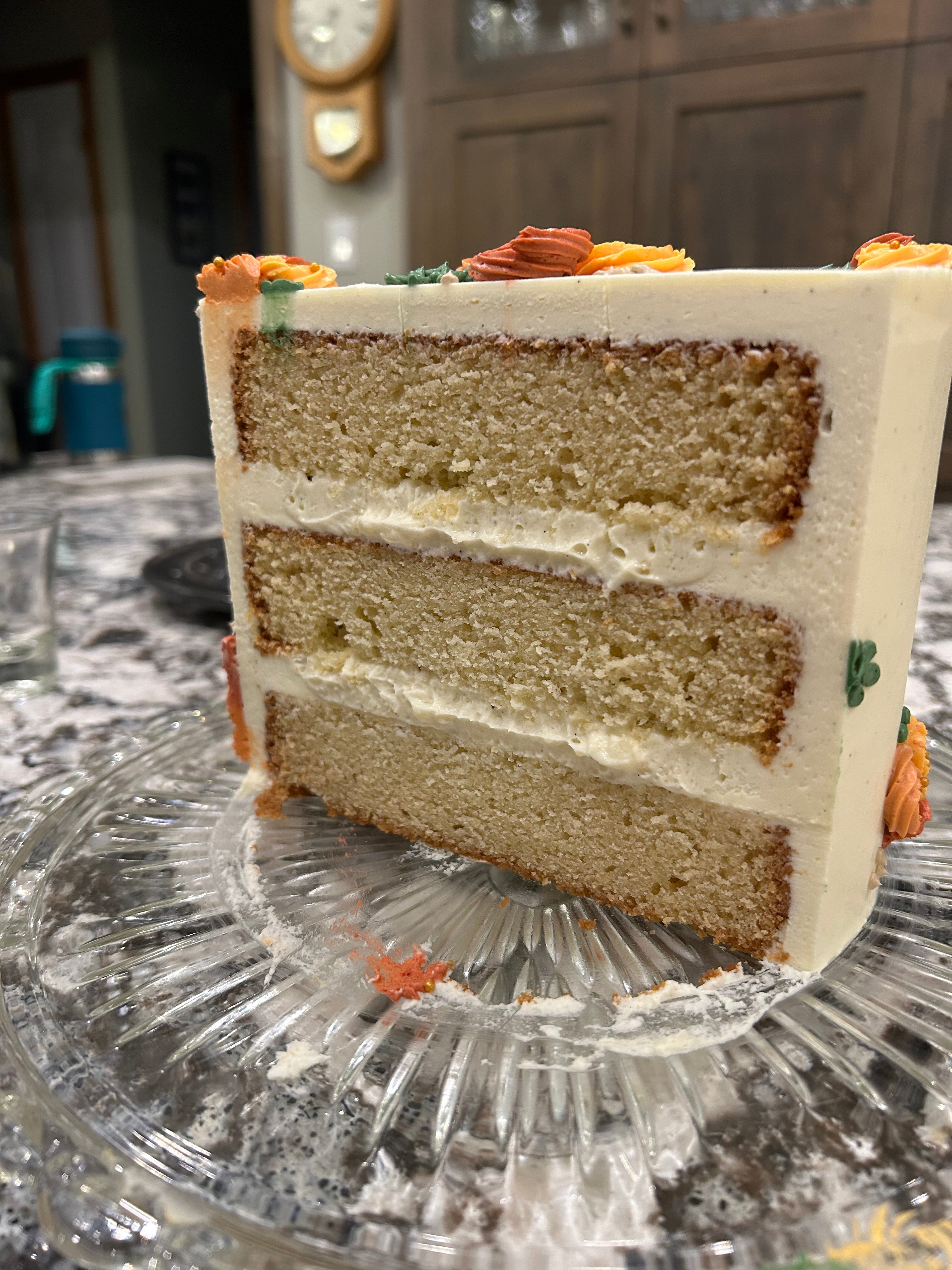 Slice of vanilla cake layered on a glass plate with decorative elements